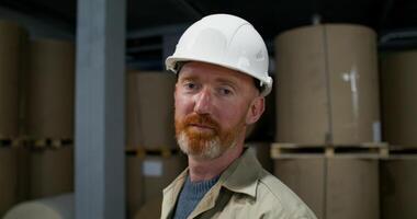 A man in a hard hat standing in front of stacks of paper video