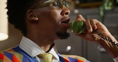 A man wearing a sweater and tie talking on a phone video