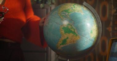 A woman holding a globe in front of a computer video