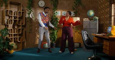 Two people standing in a room with plants and a clock video