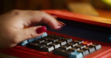 A person's hand is on top of a red calculator video