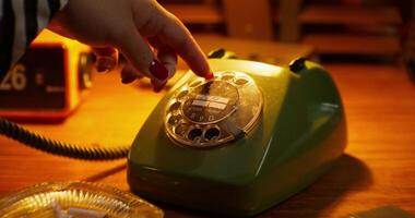 A person is pressing a button on a green telephone video