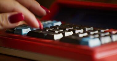 A person's hand on a red calculator video