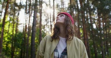 A woman in a red hat and jacket standing in the woods video