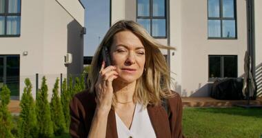 A woman talking on a cell phone in front of a house video