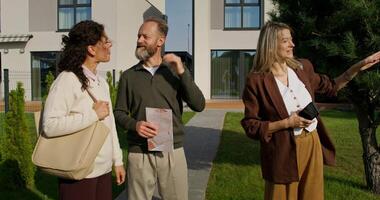 Three people standing in front of a house video