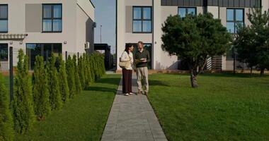 A man and woman walking along a path in front of a house video