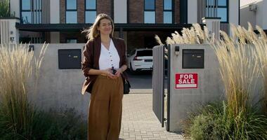 A woman standing in front of a house with a sign video