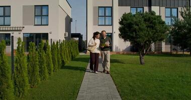 A man and woman walking down a path in front of a house video