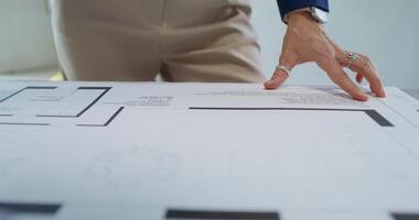 A person is pointing at a blueprint on a table video