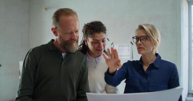 Three people standing around a table with a man pointing video