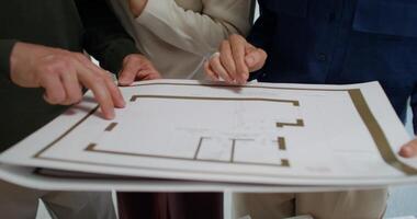 Three people looking at a blueprint on a table video