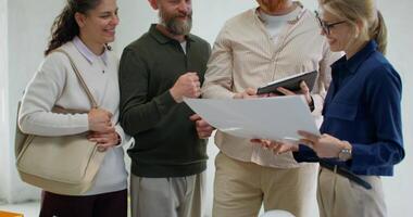 Three people standing around a table with a piece of paper video