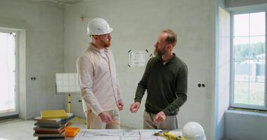 Two men in hard hats talking in a room video