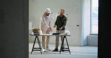 Two men in an unfinished building with a table video
