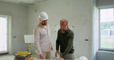 Two men in hard hats working on a construction project video