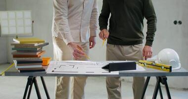 Two men standing at a table with construction plans video