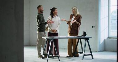 Three people standing around a table in an empty room video