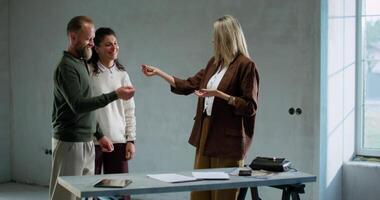 Three people standing around a table in an empty room video