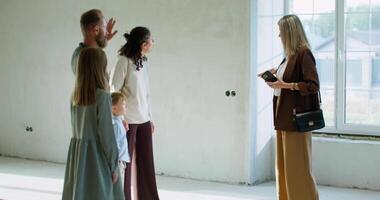 A family standing in an empty room with a woman talking to a man video