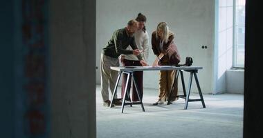 Three people standing around a table in an unfinished room video