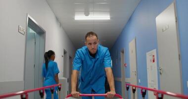 A man in blue scrub suit pushing a walker down a hallway video
