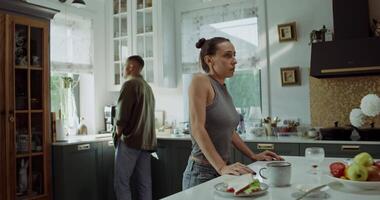 A woman standing in a kitchen with a man standing behind her video