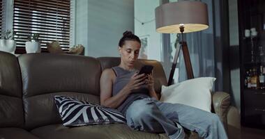 A woman sitting on a couch using her phone video