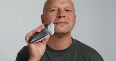 A bald man holding a black and white electronic device video