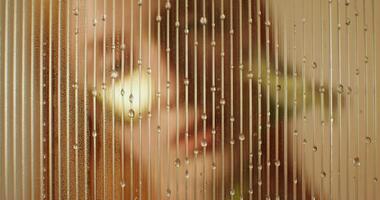 A woman is looking through a window with rain drops on it video