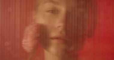 A woman is holding a flower in front of a red background video