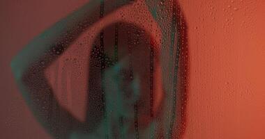A woman is standing in front of a window with water drops on it video