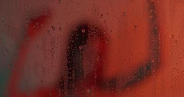 A person standing in front of a window with rain drops on it video
