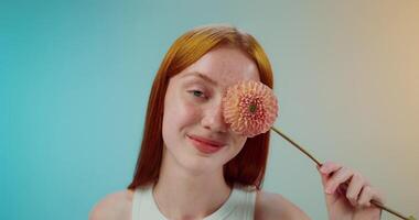 A woman with red hair holding a flower in front of her face video