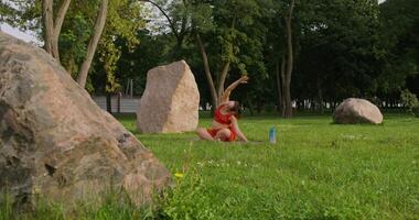 A woman is sitting on the grass near large rocks video