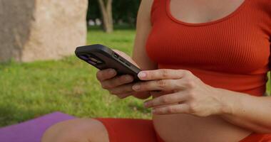 A woman in a red tank top is using her phone video