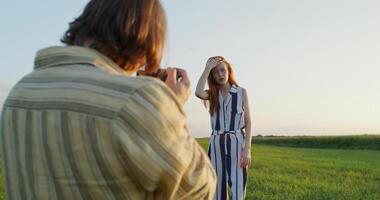 A man taking a picture of a woman in a field video