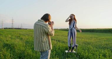 A man and woman standing in a field taking a picture video