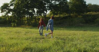 Two girls walking through a field of grass video