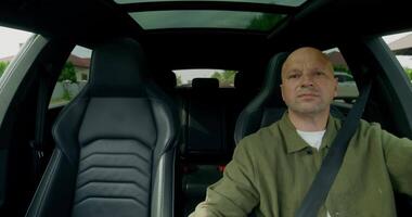 A bald man sitting in the back seat of a car video