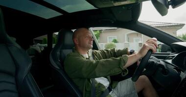 A bald man driving a car with the steering wheel in the air video