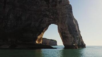 A large rock formation in the ocean with a large arch video