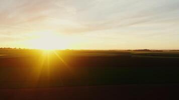 Sunset over colorful fields. from a drone, the sun's rays illuminate everything around. Bright sun low on the horizon video
