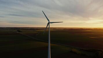 Drone of the reverse side of the wind turbine with blinking warning lights on the turbine. Wind generator among the green fields, filming at dusk from a drone. video