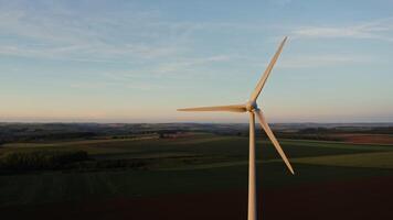 Large blades of a wind generator rotate from a breath of wind, filming from a drone at the level of the propeller. Valley with colorful fields and forests in the background. video