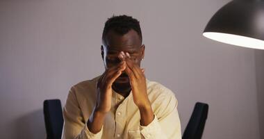 A man is sitting at a desk with his hands on his face video