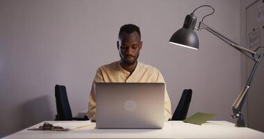 uma homem é sentado às uma escrivaninha com uma computador portátil video