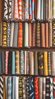 A variety of colorful fabrics are displayed on a shelf photo