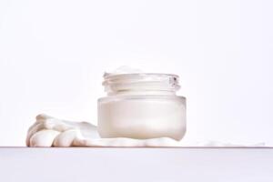 An open jar of cream with its texture on a white background. photo