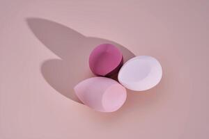 A set of makeup sponges on a pink background. photo